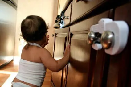 Baby resting on childproofed wooden kitchen cabinets