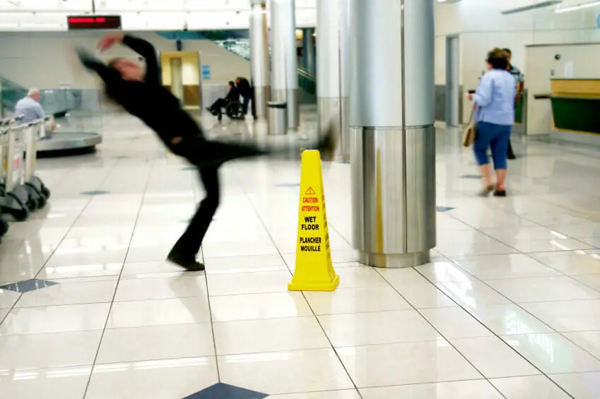 Texas Slip & Fall Premises Liability Law 2 Person in shopping center slipping and falling next to a caution wet floor sign