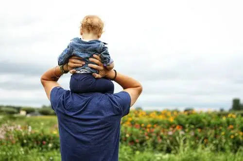 Blog 3 Father holding up child on shoulders in flower field