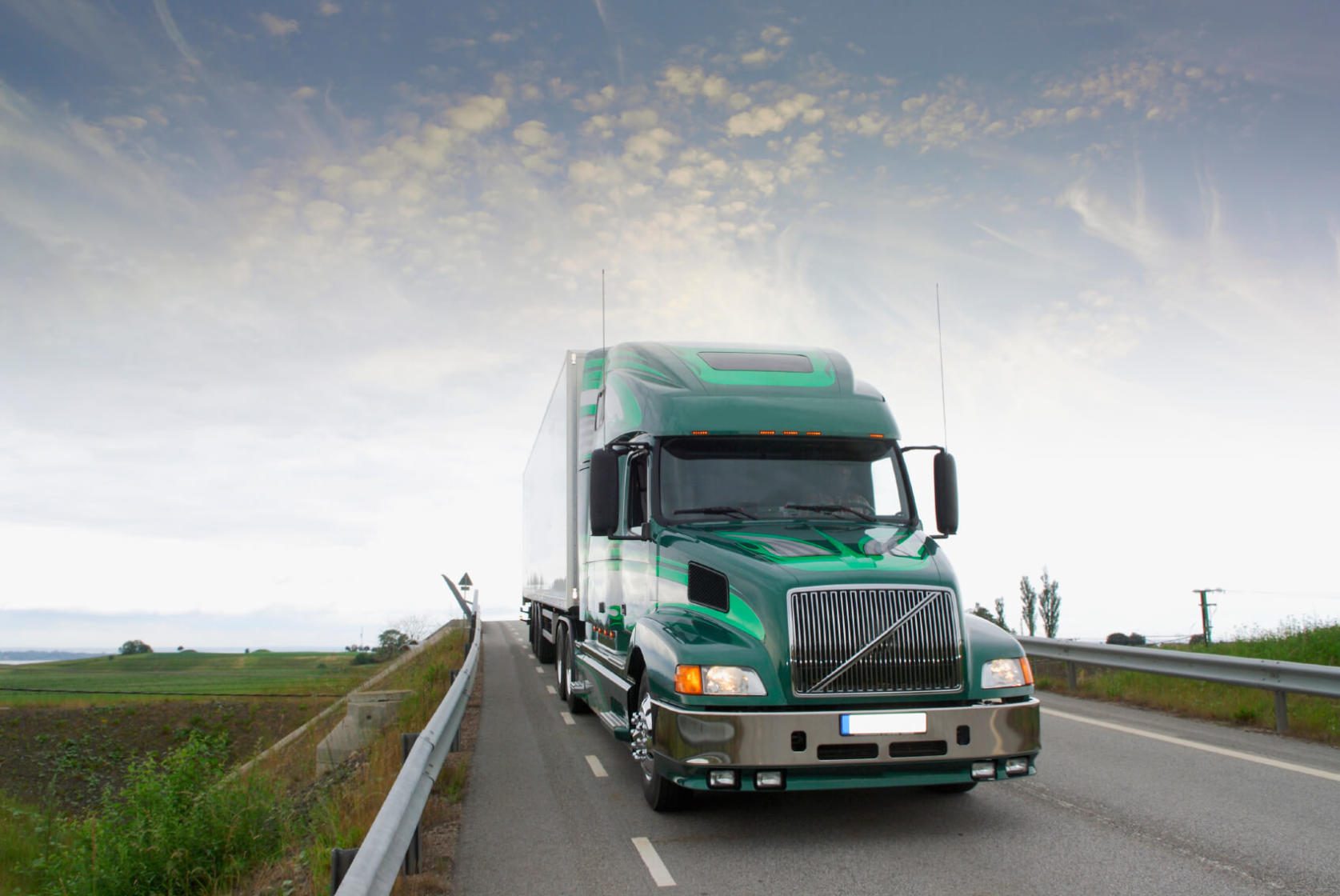 Green 18-wheeler traveling on open road