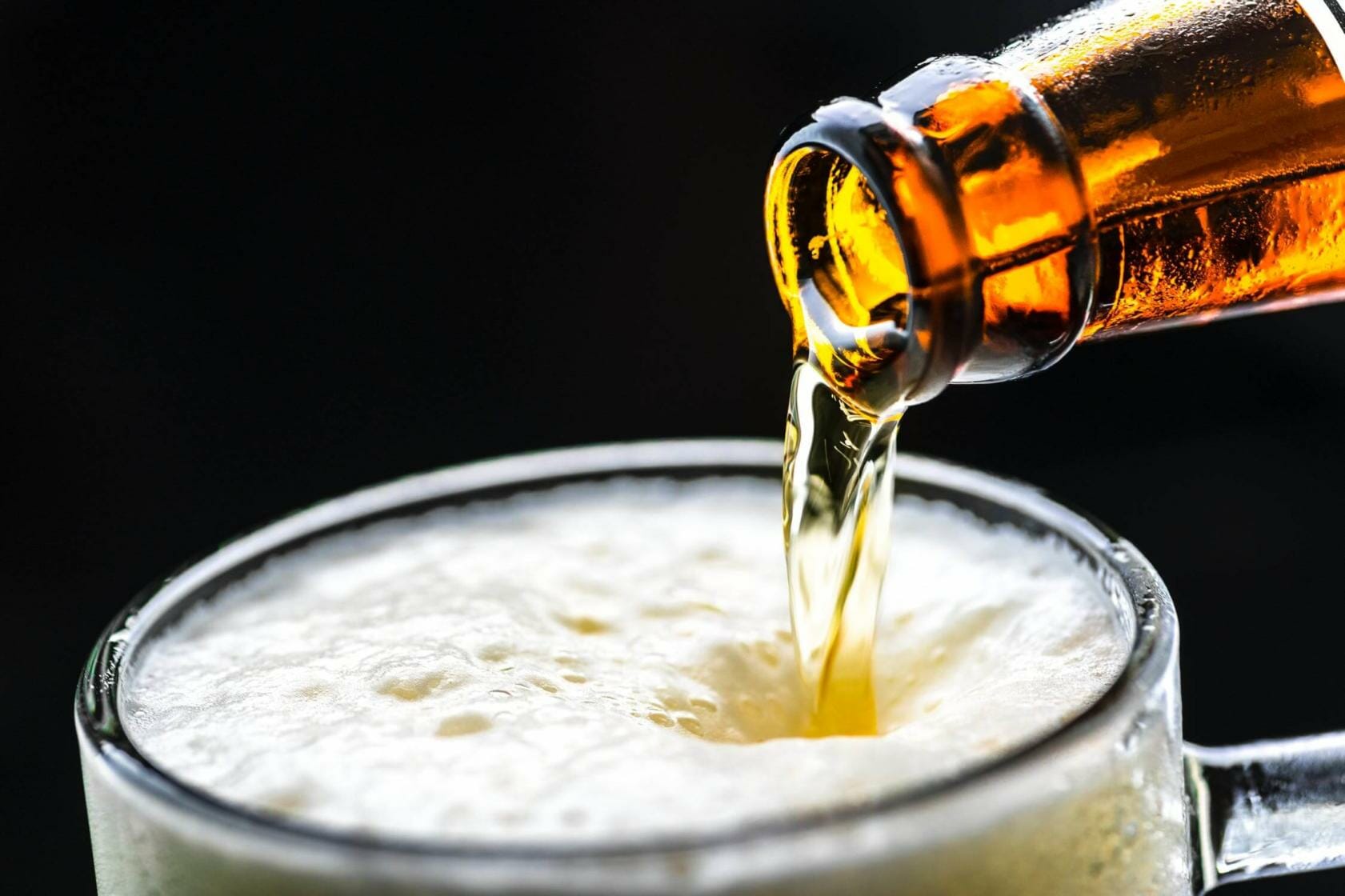 Bottle of beer being poured into a mug