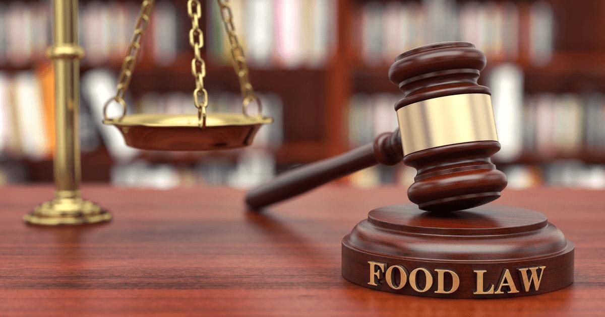 Gavel with "Food Law" embedded on it and gold scales on desk