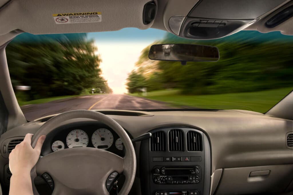 First person view of driver with one hand on the wheel